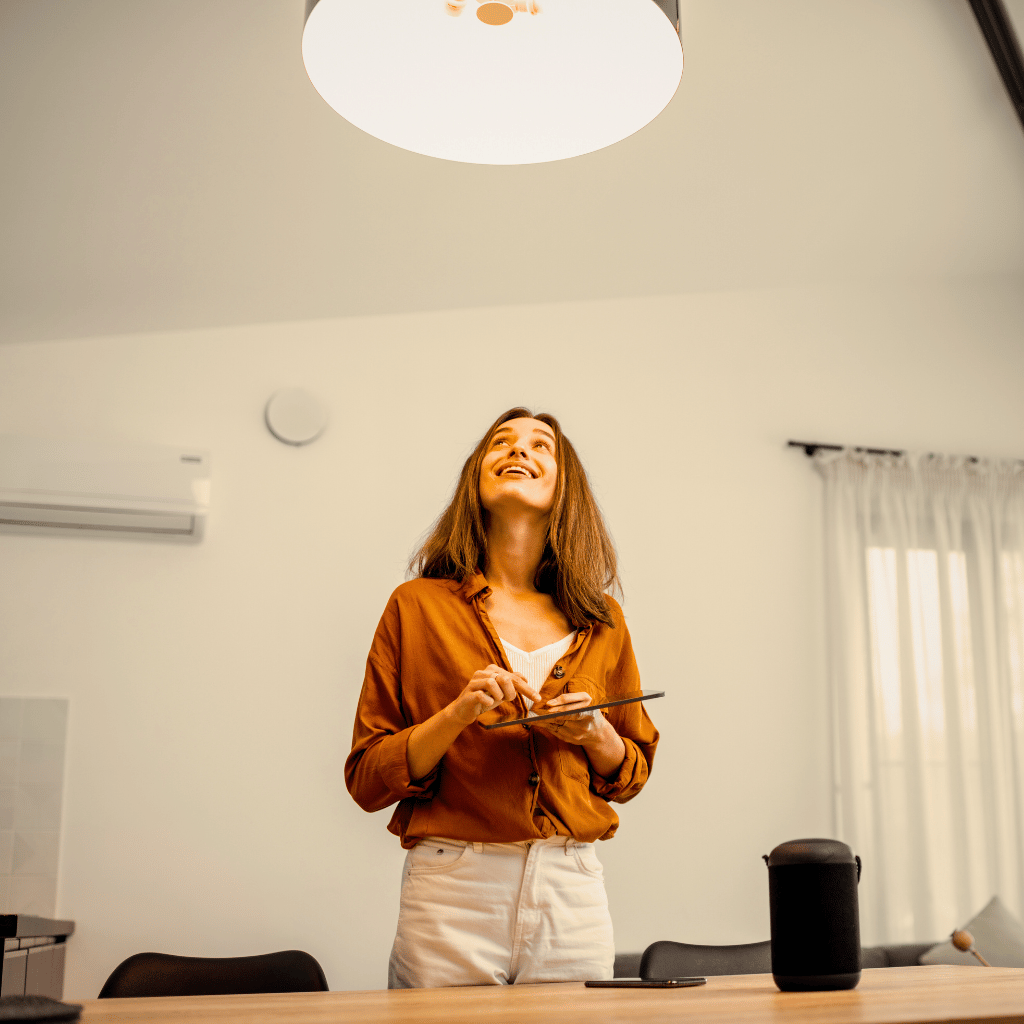 Mulher controlando iluminação inteligente com dispositivo móvel em ambiente residencial.