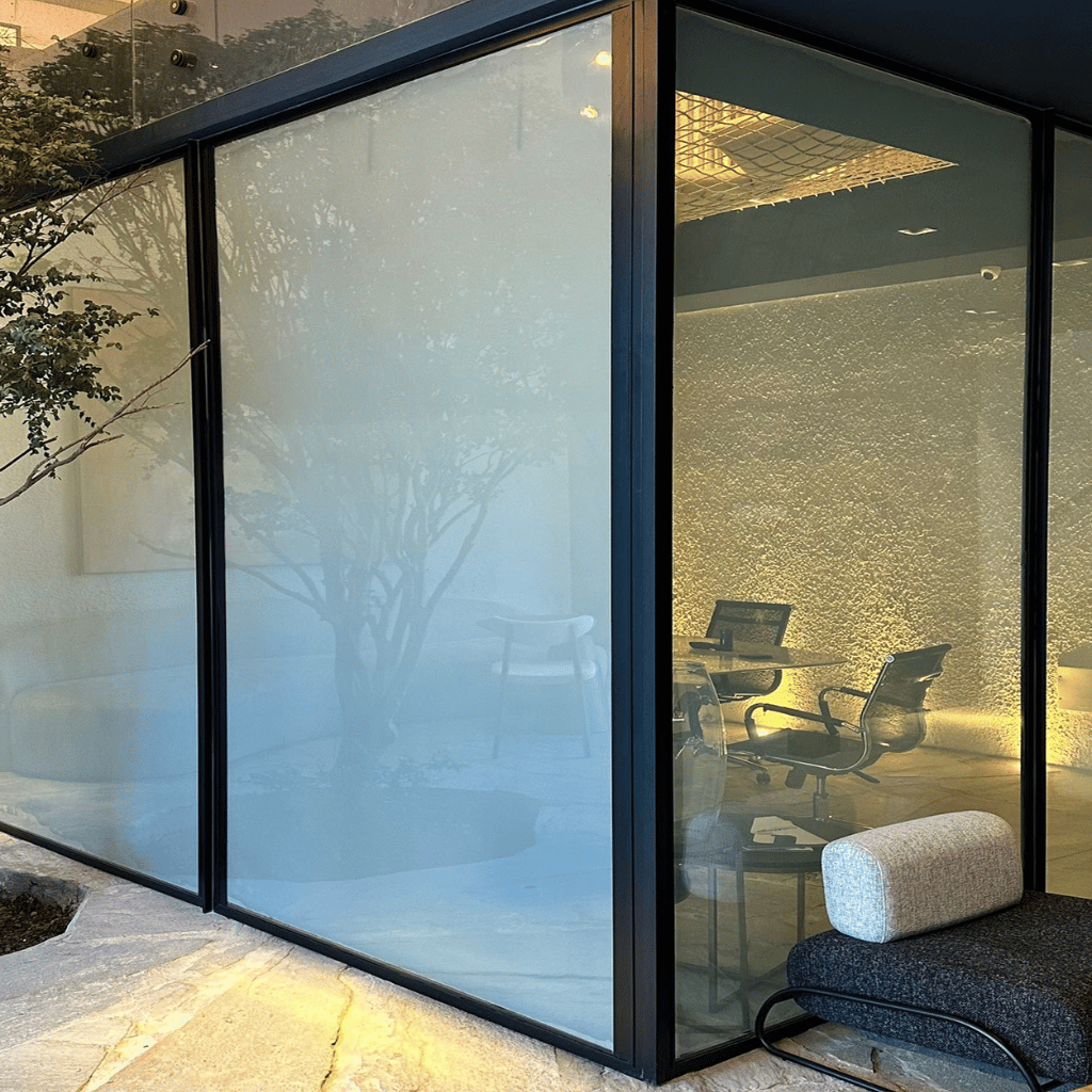 Vidros com película inteligente GLTECH alternando entre transparência e opacidade em ambiente corporativo moderno.