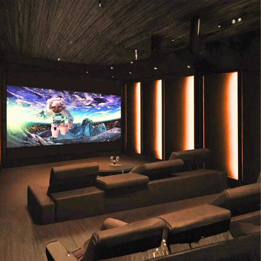 Sala de home theater com sistema GLTECH, tela de projeção ampla, som surround, iluminação cênica e automação audiovisual integrada.